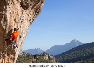 Young Male Climber Hanging By A Cliff