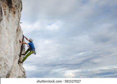 Young Male Climber Hanging By A Cliff