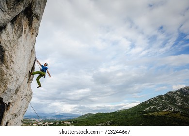 Young Male Climber Hanging By A Cliff