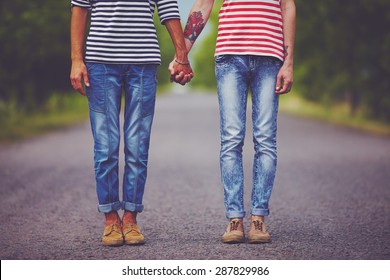 young male couple holding hands standing on their way together