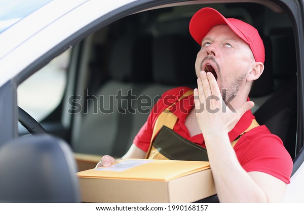 Young male\
courier driver yawns while driving\
car