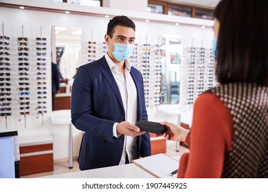 Young Male Customer In A Face Mask Taking A Spectacle Case From The Optician Hands