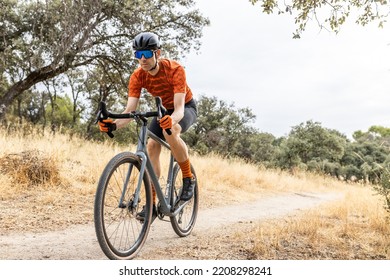 young male cyclist with his gravel bike riding in the countryside, front view
