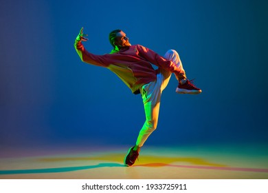 Young Male Dancer Dancing Hip-hop Isolated Over Blue Background In Neon Light