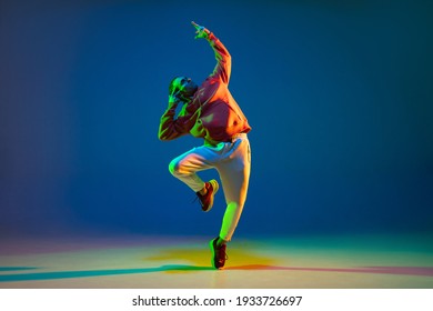 Young Male Dancer Posing Isolated Over Blue Background In Neon Light