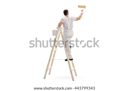 Young male decorator painting with a paint roller climbed up a ladder isolated on white background