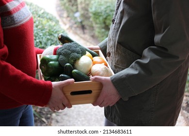 Young Male Delivering A Community Supported Agriculture (CSA) Fresh Produce Box To A Middle Aged Woman