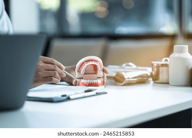 Young Male dentist holding tooth model. - Powered by Shutterstock