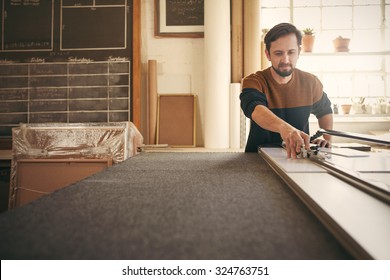 Young Male Designer Working With Concentration And Using A Tool At His Workbench In His Studio