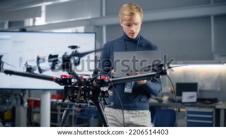 Young Male Developer Programming on Laptop Computer. Working on a New Drone Design in the Research Center Laboratory. People Creating Futuristic Unmanned Aerial Vehicle Concept.