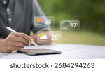 Young male developer using stylus on tablet to check augmented reality weather forecast UI outdoors; sunny, rainy, cloudy temperatures; smart technology and mobile app concept.