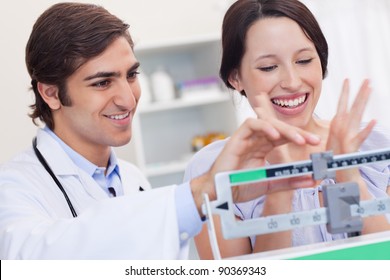 Young male doctor adjusting scale for excited patient