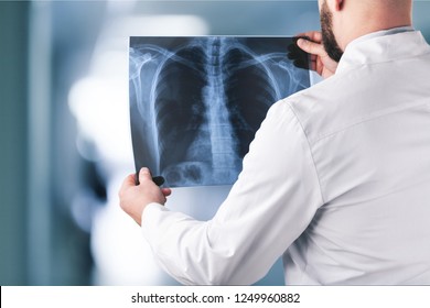 Young male doctor examining x-ray - Powered by Shutterstock