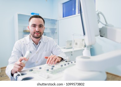 Young Male Doctor Explaining Ultrasound Scan To Pregnant Woman In Hospital