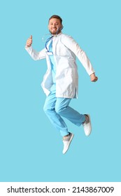 Young male doctor jumping on blue background