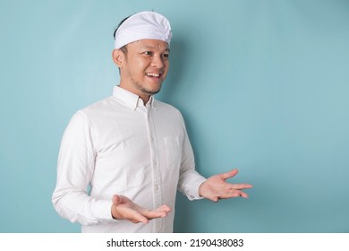 Young Male Doctor Presenting An Idea Wearing Udeng Or Traditional Headband And White Shirt While Looking Smiling On Isolated Blue Background