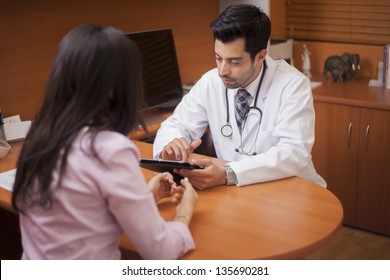 Young Male Doctor Reviewing A Patient's File On A Tablet Computer