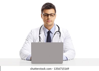 Young Male Doctor Sitting At A Desk And Working On A Laptop Isolated On White Background