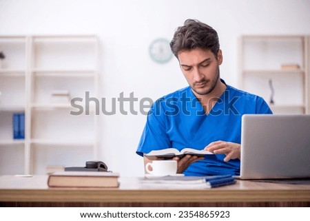 Young male doctor student reading book in the clinic
