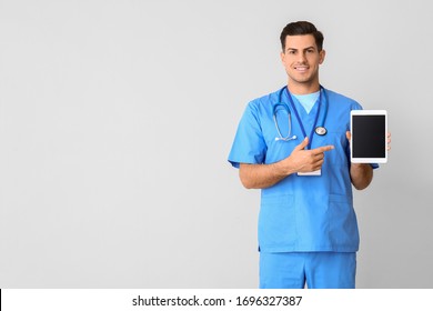 Young Male Doctor With Tablet Computer On Light Background