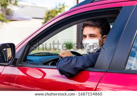 Young male driver inside car with protective face mask