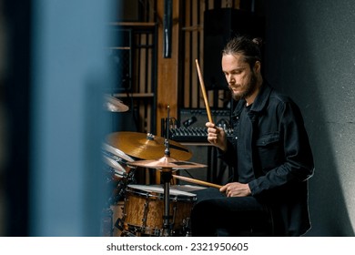 a young male drummer plays a drum kit in a recording studio at a professional musician's rehearsal recording song - Powered by Shutterstock