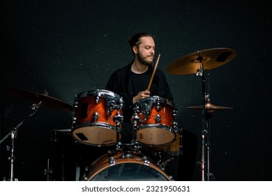 a young male drummer plays a drum kit in a recording studio at a professional musician's rehearsal recording song - Powered by Shutterstock