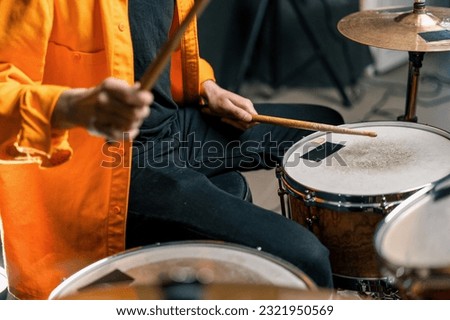 a young male drummer plays a drum kit in a recording studio at a professional musician's rehearsal recording song