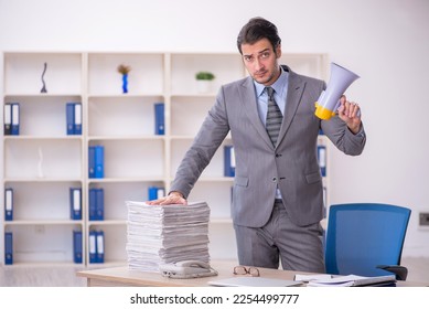 Young male employee holding megaphone at workplace - Shutterstock ID 2254499777