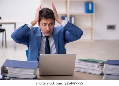 Young male employee and too much work in the office - Shutterstock ID 2254499755