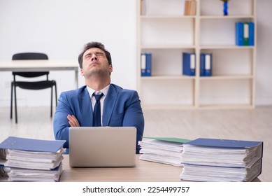 Young male employee and too much work in the office - Shutterstock ID 2254499757