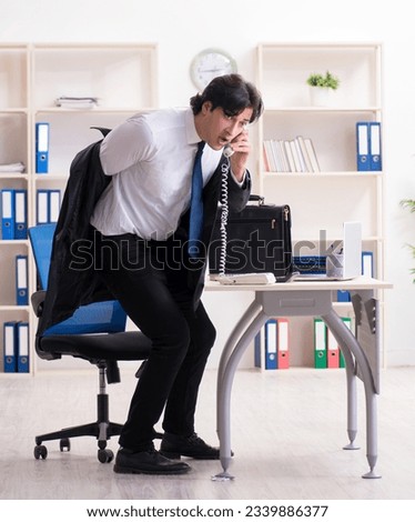 Young male employee in the office in time management concept
