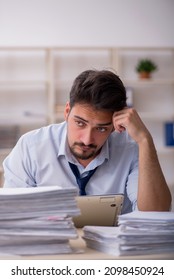 Young male employee unhappy with excessive work in the office - Shutterstock ID 2098450924