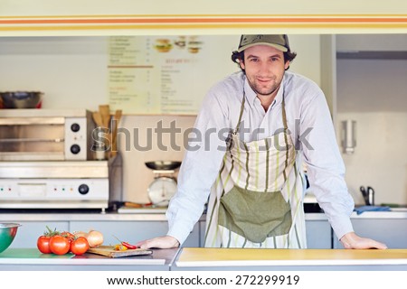 Young male entrepeneur standing confidently in his food stall where he makes and sells takeaway food 