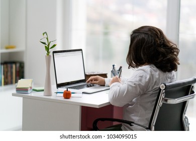 Young male entrepreneur working sitting on desk working on laptop