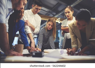Young male and female architect colleagues drawing graphic planning of interior creation project cooperating with talented teacher giving advice and correcting mistakes during training lesson  - Shutterstock ID 562244602