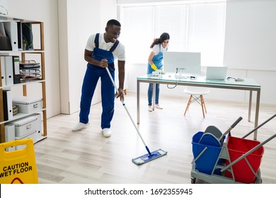 Young Male And Female Cleaners Cleaning Office