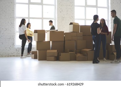 Young male and female coworkers hipsters moved to new office apartment talking making plans for unpacking boxes with staff,  group of colleagues having conversation deciding how to design space - Shutterstock ID 619268429