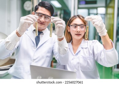 Young male and female scientist in lab coat wearing protective eyeglasses and rubber gloves while working on science experiment and research in modern laboratory using test tubes and equipment - Shutterstock ID 2256027061