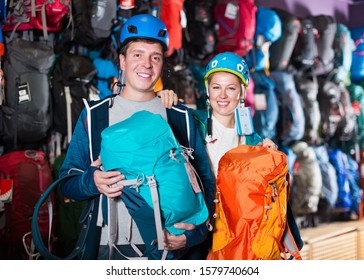 Young  Male And Female In Sports Shop To Choose Reliable Backpacks For Hiking