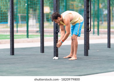 Young Male Gymnast Putting Chalk On His Hands To Prevent Slipping And Increase His Grip At An Outdoor Gym In A Health And Fitness Concept