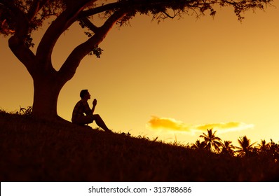 Young male with hands folded together in a beautiful setting. (prayer and desperation concept)