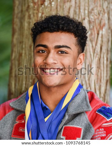 Young Male High School Senior posing for Senior photos in a beautiful park setting