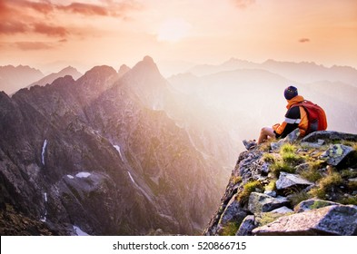 Young male hiker with backpack relaxing on top of a mountain during calm summer sunset - scenery from vacation - photo with space for your montage. - Powered by Shutterstock