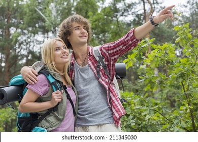 Young Male Hiker Showing Something To Woman In Forest