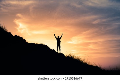 Young male hiker standing on a mountain feeling happy and inspired. Adventure, mental strength, and physical health concept.