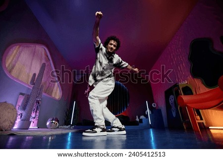 Young male hip-hop dancer moving in contemporary art studio with neon lights and art pieces