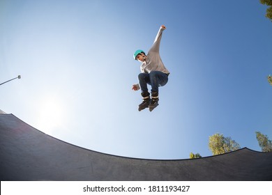 Young Male Inline Skater In Skate Park, In The Air Doing A Jump Trick. With Protective Helmet. Rollerblade