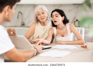 Young male insurance agent offers the best insurance terms for an elderly woman and her adult daughter. - Powered by Shutterstock