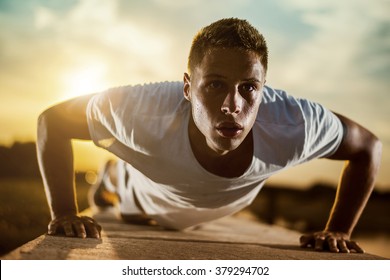 Young Male Jogger Athlete Training And Doing Workout Outdoors In City